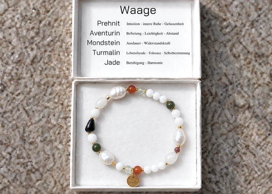 Sternzeichen-Armband Waage mit Prehnit, Aventurin, Mondstein, Turmalin, Jade und hellen Perlen in einer geöffneten weißen Schmuckschachtel mit Steinübersicht im Deckel.